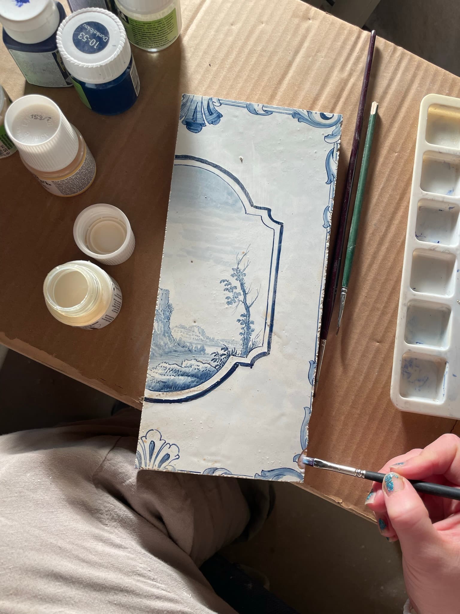 Hand bei der blauen Dekormalerei auf einer historischen Ofenkachel