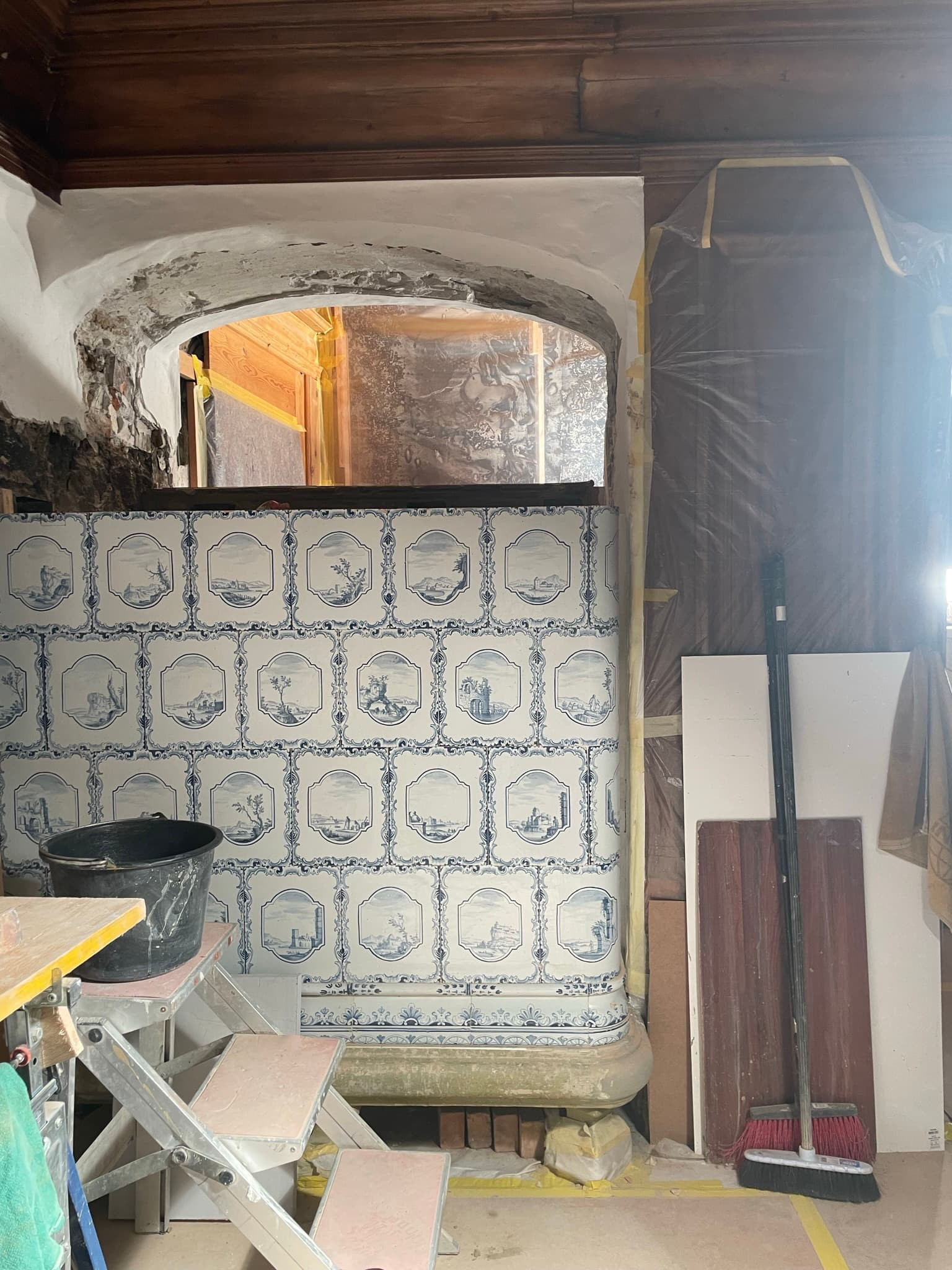 Blau-weisser Kachelofen mit sichtbarem Feuerraum während der Montage