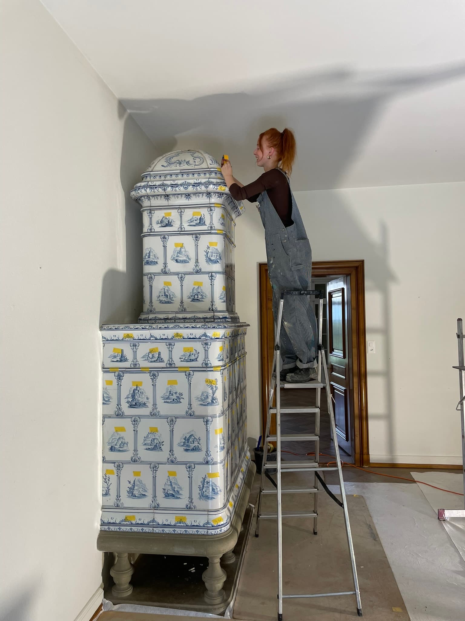 Montage eines hohen blau-weissen Kachelofens auf der Baustelle